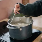 A pot of dumplings boiling in water with steam rising.