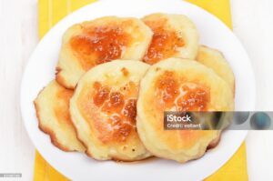 Biscuits topped with butter and honey on a serving platter.