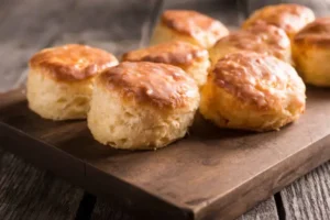 Freshly baked flaky buttermilk biscuits on a wooden tray.