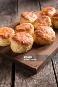 Freshly baked biscuits on a wooden table, showcasing their flaky texture.