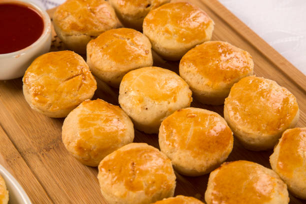 Golden, flaky biscuits stacked on a wooden plate, highlighting the results of using buttermilk or heavy cream.