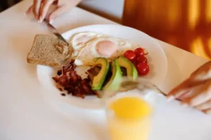 A healthy breakfast with eggs, toast, and fruit on a white table.