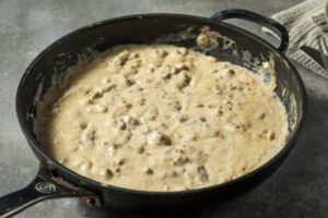 Sausage gravy simmering in a cast-iron skillet.