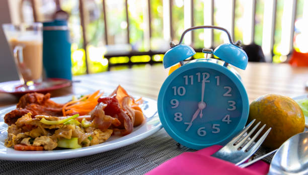 A clock with a plate of healthy food, symbolizing meal timing and health.