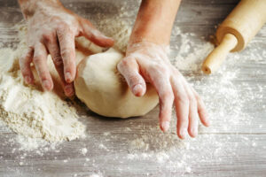  Hands kneading dumpling dough on a floured surface.