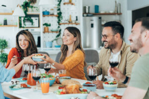 A group of friends sharing a meal at a dining table with laughter and conversation.