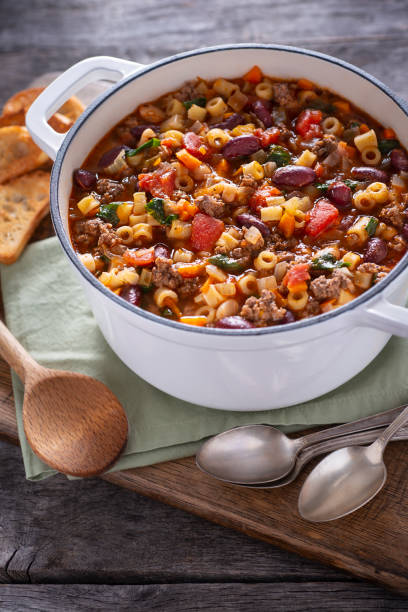 A steaming bowl of traditional Pasta Fagioli with beans, pasta, and fresh herbs.