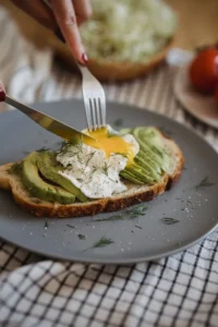 Healthy breakfast plate with eggs, avocado, and toast.