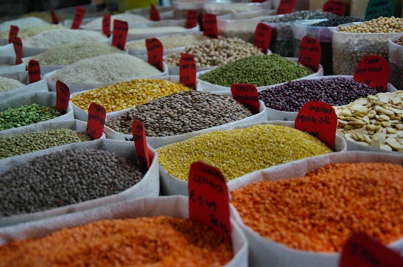 A vibrant display of various types of beans and lentils in sacks at a market, showcasing their diversity and versatility.