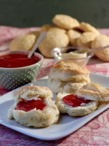 Warm 3 ingredient biscuits served with butter and jam on a plate.