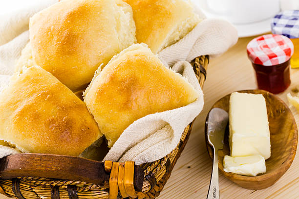 Golden brown homemade biscuits in a basket with butter on the side.