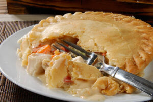 A creamy chicken pot pie with a golden crust served on a rustic table.