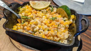 Elote salad with grilled corn, cheese, and herbs in a green bowl - a perfect pairing with shrimp