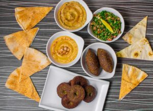 A delicious Middle Eastern platter featuring falafel made with fava beans, creamy hummus with chickpeas, tabbouleh salad, and pita bread.