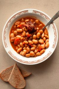 A bowl of seasoned beans garnished with fresh herbs, showing how to make beans taste good.