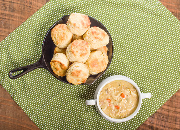 Freshly baked biscuits and dumplings in a bowl of soup on a wooden table.