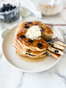  Fluffy pancakes and blueberry muffins served on a breakfast table.