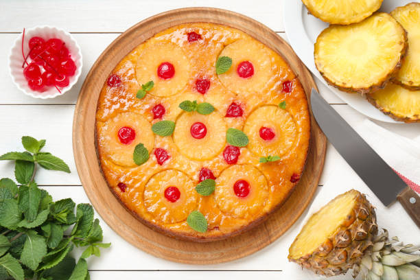 A freshly baked pineapple upside-down cake garnished with cherries and mint leaves