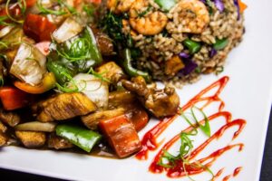 Chicken and shrimp stir fry with colorful vegetables, rice, and a drizzle of sauce, seasoned to let the shrimp shine