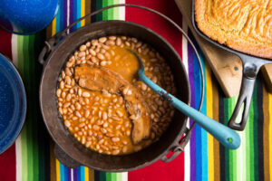 A pot of cooked beans with a slice of pork, showcasing the benefits of soaking beans before cooking.