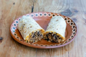  A delicious taco filled with black beans, rice, and cheese, served on a decorative ceramic plate.