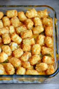 Golden and crispy tater tot casserole with cheese and vegetables in a glass baking dish.