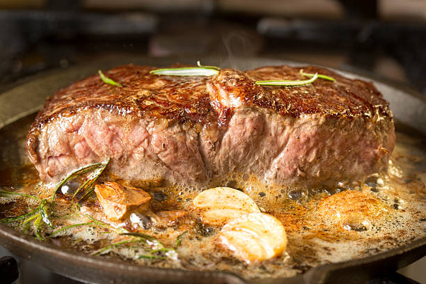 Searing a steak in a cast iron pan with butter and garlic