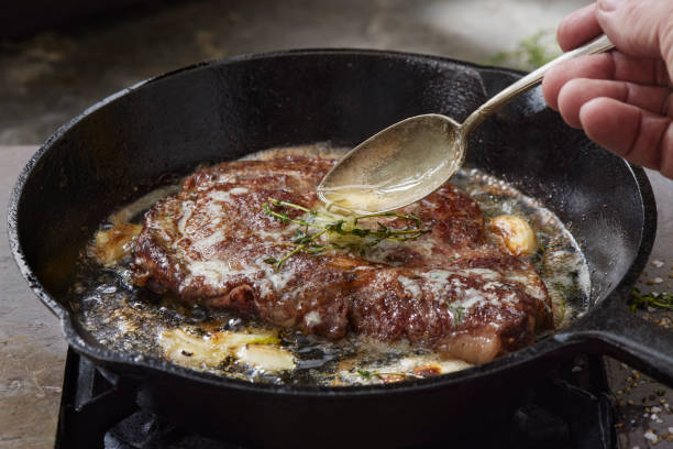  Steak being seared in a cast iron pan with garlic and butter